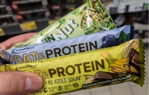 Hand holding oat and protein bars in different flavors at a store