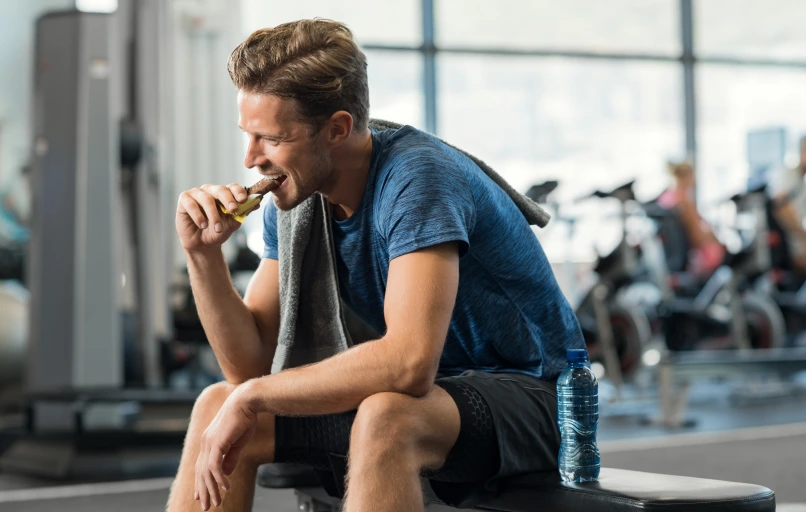 Man eating a protein chocolate bar outdoors after exercise