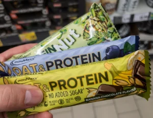 Hand holding oat and protein bars in different flavors at a store