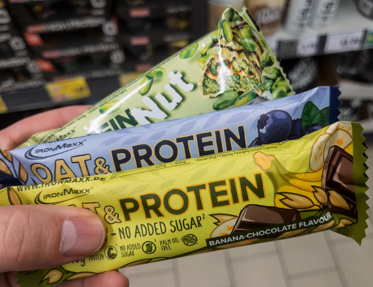 Hand holding oat and protein bars in different flavors at a store