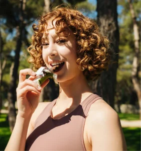 Woman eating a protein chocolate bar outdoors after exercise