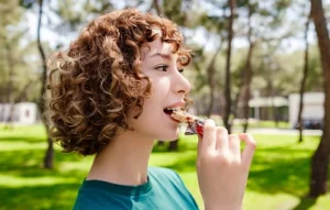 Woman eating a protein chocolate bar outdoors